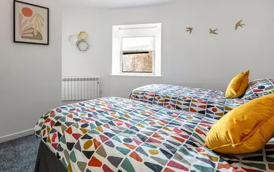 a bedroom with two beds with a colorful comforter at Castle Street Apartments - Luxury Ettrick Apartment in Rothesay