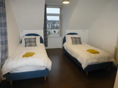 two beds in a room with a window at Quiet Street's Flat with free Parking near Town Centre in Largs