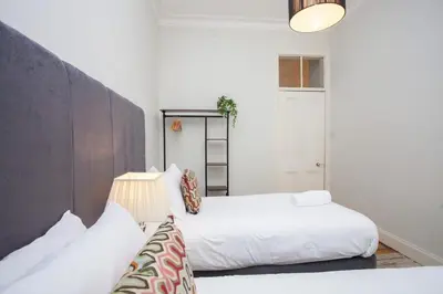 two beds in a room with white walls at Lovely Flat in Ideal Location in Glasgow