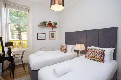 a bedroom with two beds and a desk and a window at Lovely Flat in Ideal Location in Glasgow