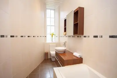 a bathroom with a sink and a toilet and a window at Lovely Flat in Ideal Location in Glasgow