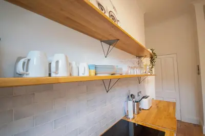 a kitchen with a shelf with dishes on it at Stunning 3 Bed Flat in the Heart of the West End in Glasgow