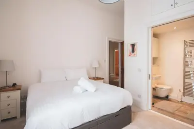 a white bedroom with a large bed and a bathroom at Stunning 3 Bed Flat in the Heart of the West End in Glasgow
