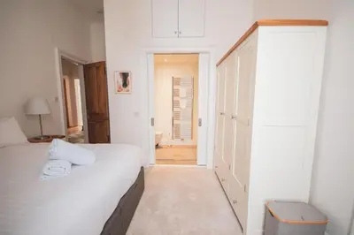 a white bedroom with a bed and a bathroom at Stunning 3 Bed Flat in the Heart of the West End in Glasgow