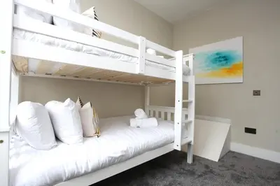 a bedroom with two bunk beds with white pillows at Three Bedroom Upper Flat in Jordanhill in Glasgow