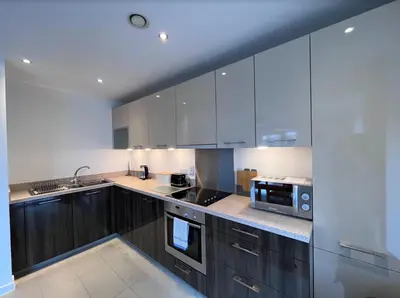 a kitchen with white cabinets and a sink and a microwave at Stylish Newly Decorated 2 Bed in Glasgow