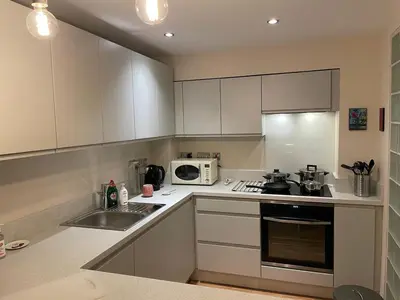 a kitchen with white cabinets and a sink and a microwave at The Art Flat Woodlands in Glasgow
