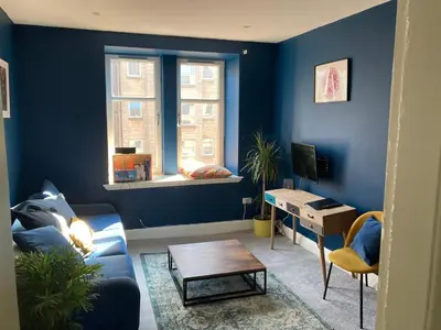 a blue living room with a couch and a table at 2 Bedroom Oasis in Glasgow City Centre in Glasgow