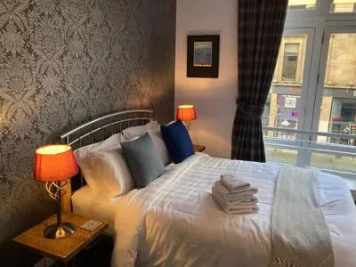 a bedroom with a bed with two lamps and a window at The Art Flat Glasgow in Glasgow