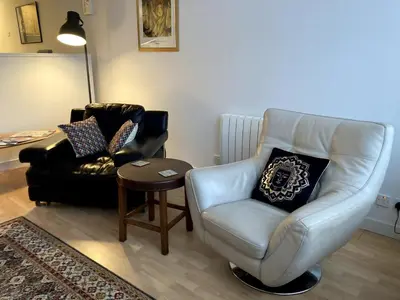 a living room with a white chair and a table at The Art Flat Glasgow in Glasgow