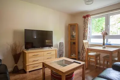 a living room with a tv and a table at Homely Flat close to Centre with Free Parking in Glasgow