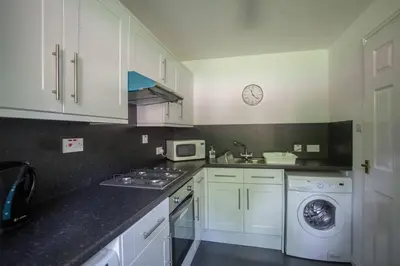 a kitchen with white cabinets and a washing machine at Homely Flat close to Centre with Free Parking in Glasgow