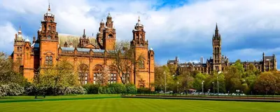 a large brick building with two towers and a grass field at Homely Flat close to Centre with Free Parking in Glasgow