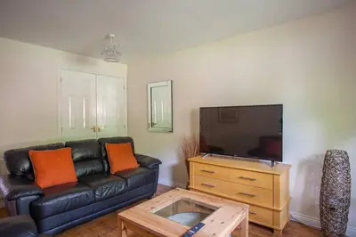 a living room with a black leather couch and a tv at Homely Flat close to Centre with Free Parking in Glasgow