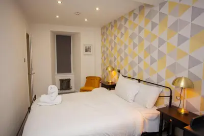 a bedroom with a white bed with a geometric wall at Beautiful 2 Bed Flat with a Private Terrace in Glasgow