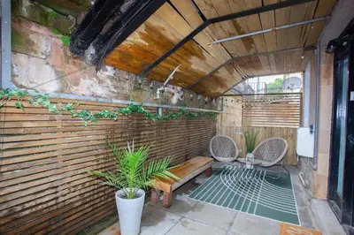 a patio with two chairs and a wooden wall at Beautiful 2 Bed Flat with a Private Terrace in Glasgow