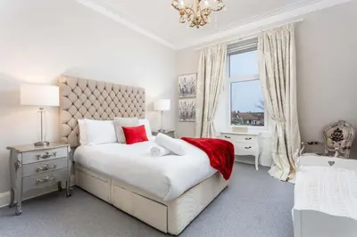 a white bedroom with a large bed and a window at The Bradshaw in Prestwick