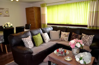 a living room with a brown leather couch with pillows at Double Room in Riverside Apartment - C in Glasgow