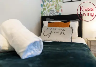 a bedroom with a bed with a pillow with the words be our guest at Drumpellier Apartment by Klass Living Coatbridge in Coatbridge