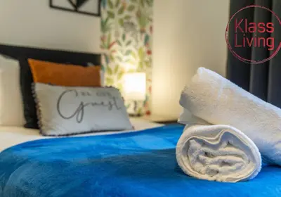 a blue bed with a towel on top of it at Drumpellier Apartment by Klass Living Coatbridge in Coatbridge