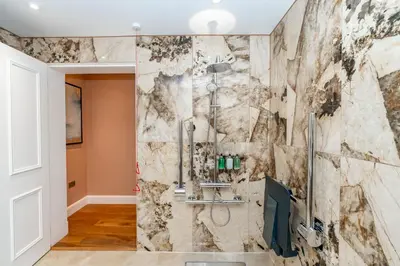 a bathroom with a stone wall at Dragon Suites Luxury Apartments at 9 Albyn Place in Edinburgh