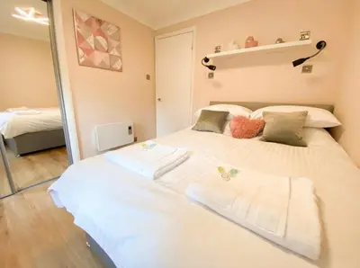 a bedroom with a large white bed with towels on it at Central two bedroom, Free private parking in Glasgow