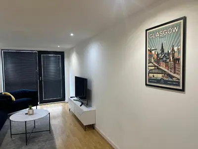 a living room with a couch and a tv and a table at Glasgow River Clyde Hydro Aprt in Glasgow