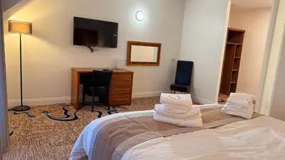 a bedroom with a bed and a desk and a television at Kelpies Hotel Falkirk in Falkirk