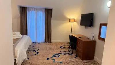 a hotel room with a bed and a desk and a television at Kelpies Hotel Falkirk in Falkirk