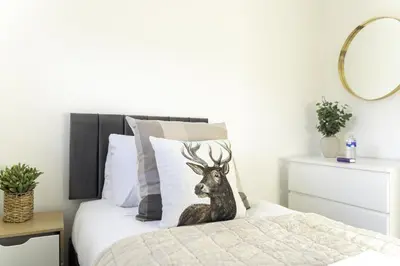 a bedroom with a bed with a deer applique on it at Dunbank Apartment in Clydebank
