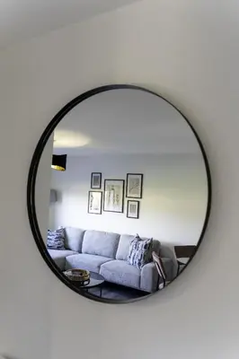 a mirror reflecting a couch in a living room at Dunbank Apartment in Clydebank