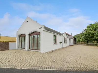 a white house on a brick road at The Stables at Daldorch in Mauchline
