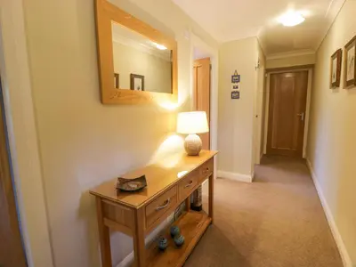 a hallway with a table with a lamp and a mirror at The Stables at Daldorch in Mauchline
