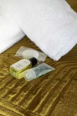 a bottle of sunscreen and a tube of toothpaste on a bed at 3 BDR House By Caledonia Luxe Stays Short Lets & Serviced Accommodation Airdrie in Airdrie