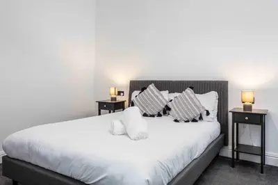 a bedroom with a white bed with two night stands at The Fairlie Suite No2 in Prestwick