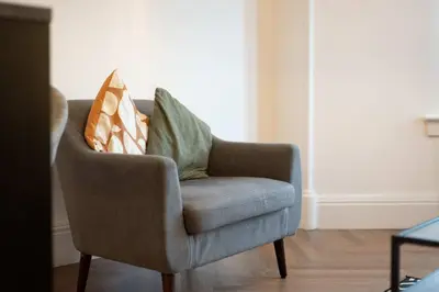 a chair with pillows on it in a living room at The Fairlie Suite No2 in Prestwick