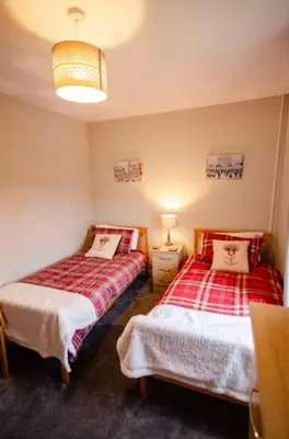 a bedroom with two beds and a lamp at Spacious 4-Bedroom House in Glenboig in Glenboig