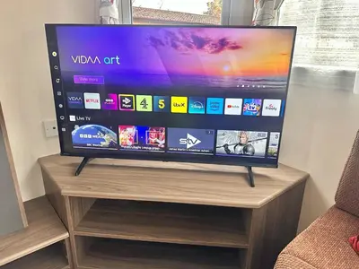 a flat screen tv sitting on top of a wooden stand at Delta, Bromley 4-Bedroom Located in Uddingston, Glasgow at Maryville Caravan Site in Uddingston