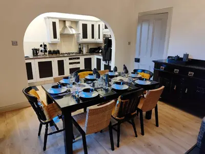 a dining room table with chairs and a kitchen at Bella Vista Manor - with elevated views over Rothesay & Loch Striven in Rothesay