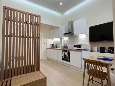 a kitchen with white cabinets and a table and a television at Edinburgh city centre 1Bed flat near Castle & Uni in Edinburgh