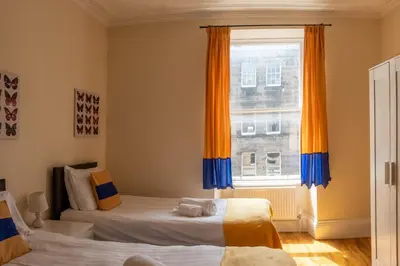 two beds in a room with a window at 3 Bedroom Apartment with castle views in Edinburgh