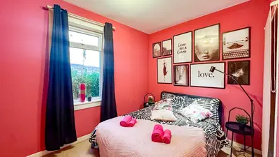 a bedroom with pink walls and a bed with pink shoes on it at Holly street house with Separate Entrance,Glasgow edge in Clydebank