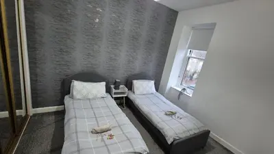a room with two beds and a window at Bellshill Central Apartment in Bellshill