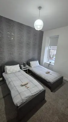 a bedroom with two beds and a window at Bellshill Central Apartment in Bellshill