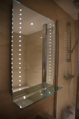 a mirror in a bathroom with a glass shelf at Edinburgh Pearl Apartments - Dalry House Residence in Edinburgh