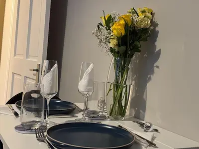 a table with a vase of yellow flowers and glasses at Peaceful Place in Falkirk