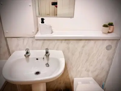 a white bathroom with a sink and a mirror at Modern apartment in Stenhousemuir in Stenhousemuir