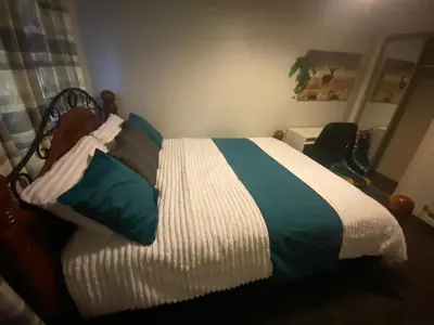 a bedroom with a bed with a green and white comforter at Harbury Lodge in Scotstoun West Station