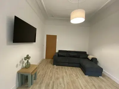 a living room with a black couch and a tv at 1 Smithhills Sleeps 5 Central and Spacious in Paisley