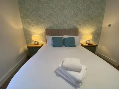 a bedroom with a large white bed with blue pillows at 1 Smithhills Sleeps 5 Central and Spacious in Paisley